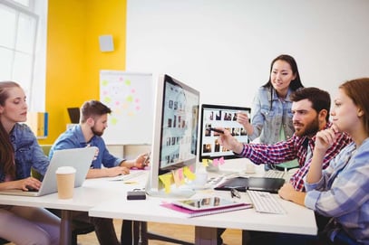 Businessman showing computer screen to coworkers in creative office-2